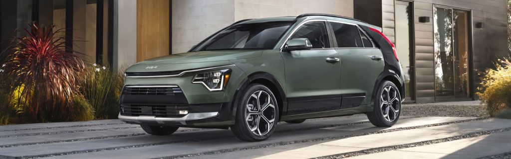 Green compact SUV parked outside home.