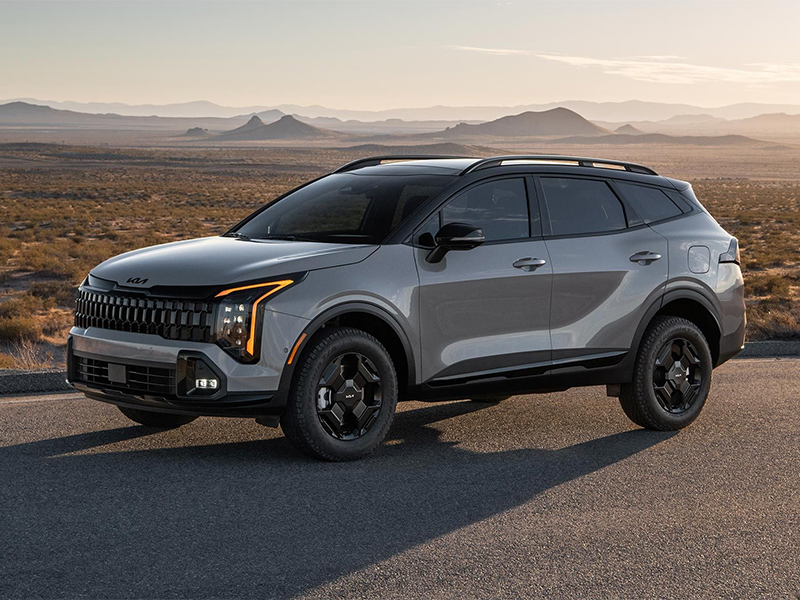 2026 Kia Sportage SUV in gray with black wheels parked on an open desert highway at sunset.