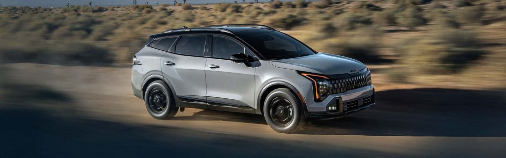 A silver Kia Sportage driving through a desert landscape.