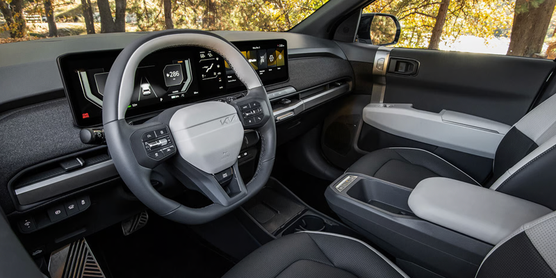 Interior view of a modern car dashboard and steering wheel, featuring digital displays and a sleek design.